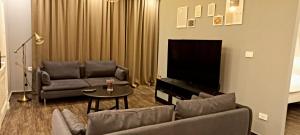 uma sala de estar com um sofá e uma televisão de ecrã plano em Elite Corner Apartment em Ţāb Kirā‘