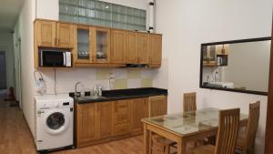 a kitchen with wooden cabinets and a table and a washing machine at Best Price Hồ Gươm Apartments for Long Stay in Hanoi