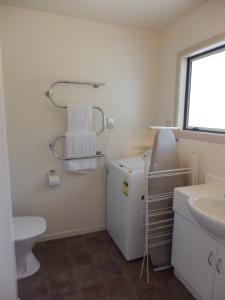een badkamer met een wastafel en een witte koelkast bij Wakatipu View Apartments in Queenstown