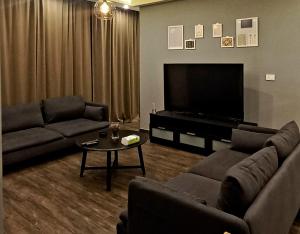 a living room with two couches and a flat screen tv at Elite Corner Apartment in Ţāb Kirā‘