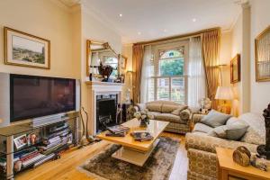 a living room with a large television and a table at Georgiana's Guesthouse in London