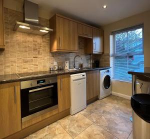 una cucina con armadi in legno, lavatrice e asciugatrice di Spacious Townhouse with Parking a Telford