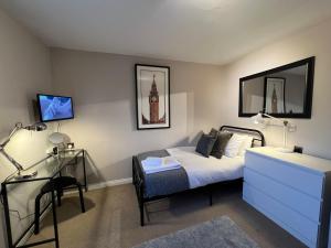 a bedroom with a bed and a dresser and a clock tower at Spacious Townhouse with Parking in Telford