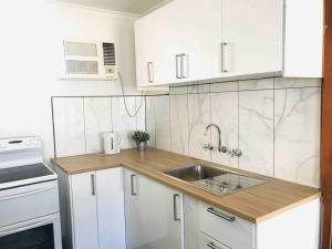 a kitchen with white cabinets and a sink at Beachside Unit Brighton in Adelaide