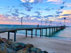 a pier on the beach with a person walking on it at Beachside Unit Brighton in Adelaide