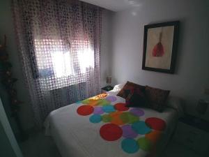 un lit avec une couette colorée dessus dans une chambre dans l'établissement El Vinilo. Aparcamiento exterior gratuito, à Teruel