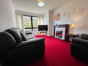 sala de estar con sofá negro y alfombra roja en Anniesland Glasgow 1bd Flat - Free Parking en Glasgow
