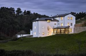 a large white house on a grassy hill at Finca Portizuelo in Luarca