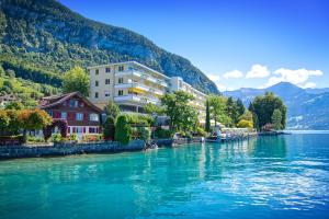 Blick auf einen Fluss mit Gebäuden und Bergen in der Unterkunft BEATUS Wellness- & Spa-Hotel in Merligen