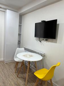 バクリアニにあるBakuriani Mix , Cozy 407のテーブルと椅子2脚、壁掛けテレビが備わる客室です。