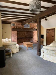 a living room with two couches and a brick fireplace at Brookside Barn in Lichfield