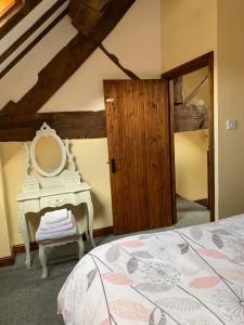 a bedroom with a bed with a mirror and a table at Brookside Barn in Lichfield