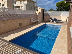 a blue swimming pool with a bench next to a building at OLIVA HOLIDAYS 1 in Oliva