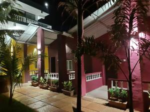 a house with pink and yellow walls and palm trees at Sandbanks Beach Resort in Arambol