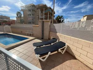 un par de sillones en un balcón junto a la piscina en OLIVA HOLIDAYS 1, en Oliva