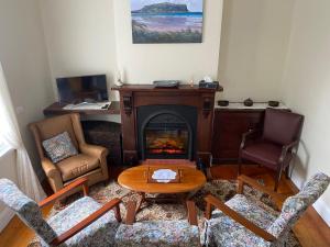 a living room with a fireplace and a table and chairs at Harbour Master's Cottage in Stanley