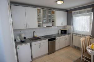 una cocina con armarios blancos y fregadero en Kuća za odmor Martin, en Sveti Martin na Muri