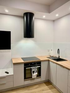 a kitchen with white cabinets and a black stove top oven at Apartament Nowomiejska in Suwałki