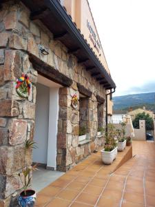 a stone building with potted plants on a patio at Hotel Alma Rosa in Navaluenga