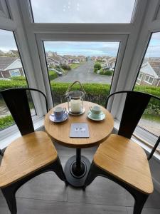 a table and two chairs in a room with a window at Newly renovated 1st floor apartment with mountain views in Tywyn