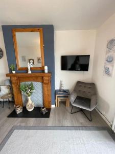 a living room with a mirror and a chair at Newly renovated 1st floor apartment with mountain views in Tywyn