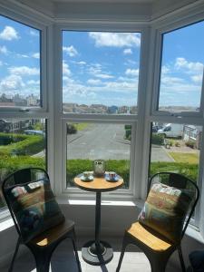 a room with two chairs and a table in front of a window at Newly renovated 1st floor apartment with mountain views in Tywyn