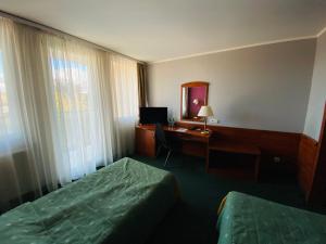 a hotel room with a bed and a desk with a computer at Hotel Pietrak in Trzemeszno