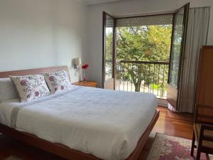 a bedroom with a large bed and a balcony at RIVER SUITE Apartment in Portugalete