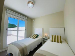 2 Betten in einem Zimmer mit einem großen Fenster in der Unterkunft Summerlandrota Argüelles 4 in Rota