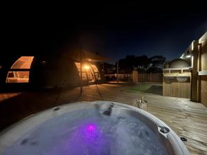 a bath tub on a deck at night at Moonlight Dome Tent in Tenby