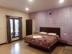 a bedroom with a large bed with a purple wall at The Atmosphere Resort Kotagiri By LexStays in Kotagiri