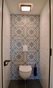a bathroom with a toilet and a tile wall at Luxe vakantievilla Zoutelande in Zoutelande