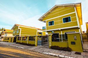 un edificio amarillo con una valla al lado de una calle en ApartPousada Residencial dos Reis en São Francisco do Sul