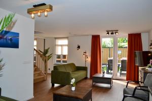 a living room with a green couch and a television at Luxe vakantievilla Zoutelande in Zoutelande