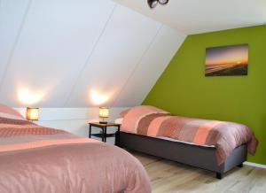 a bedroom with two beds and a green wall at Luxe vakantievilla Zoutelande in Zoutelande