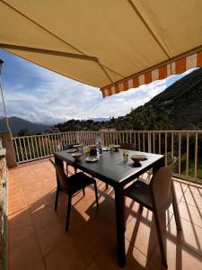 uma mesa e cadeiras numa varanda com um guarda-sol em Maison Purrussoni em Levie