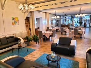 ブルボンヌ・レ・バンにあるHotel Restaurant Herardのソファ、テーブル、椅子が備わるレストラン