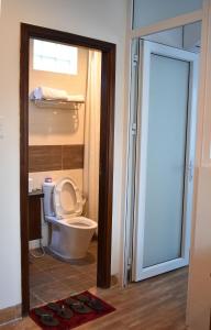 a bathroom with a toilet and a glass door at Danang Beach Homestay in Danang