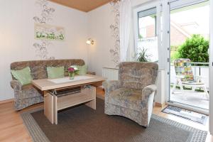 a living room with a couch and a table and a chair at Ferienwohnungen Haus Saathoff in Bensersiel +53 photos