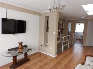 uma sala de estar com uma mesa e uma televisão na parede em Alojamiento Altos del Pacífico em Iquique