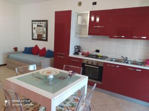 een keuken met rode kasten en een tafel met een wastafel bij AI NIPOTI in Pescantina