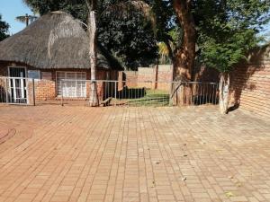 a brick building with a tree and a fence at Kaste guesthouse Tzaneen in Tzaneen
