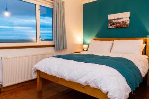 a bedroom with a bed with a green wall and a window at Atlantic views at Arnisdale House 