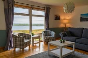 a living room with a couch and chairs and a large window at Atlantic views at Arnisdale House 