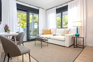 een woonkamer met een witte bank en een tafel bij Genteel Home Arruzafa in Córdoba