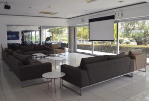 una sala de espera con sofás y una pantalla de proyección en UC Hall Residence, en Nicosia