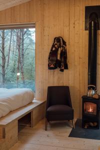 a bedroom with a bed and a chair and a stove at Youza ecolodge in La Couture-Boussey