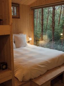 a bed in a room with a large window at Youza ecolodge in La Couture-Boussey