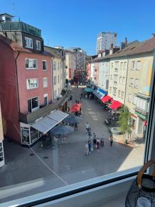 Elle offre une vue sur une rue de la ville depuis sa fenêtre. dans l'établissement Wilhelmsapartment, à Friedrichshafen