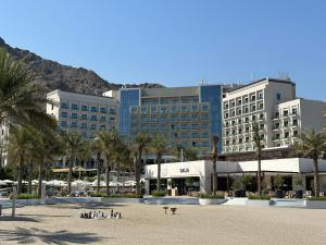 a large building with palm trees in front of it at Address Beach Resort Residence Fujairah in Fujairah